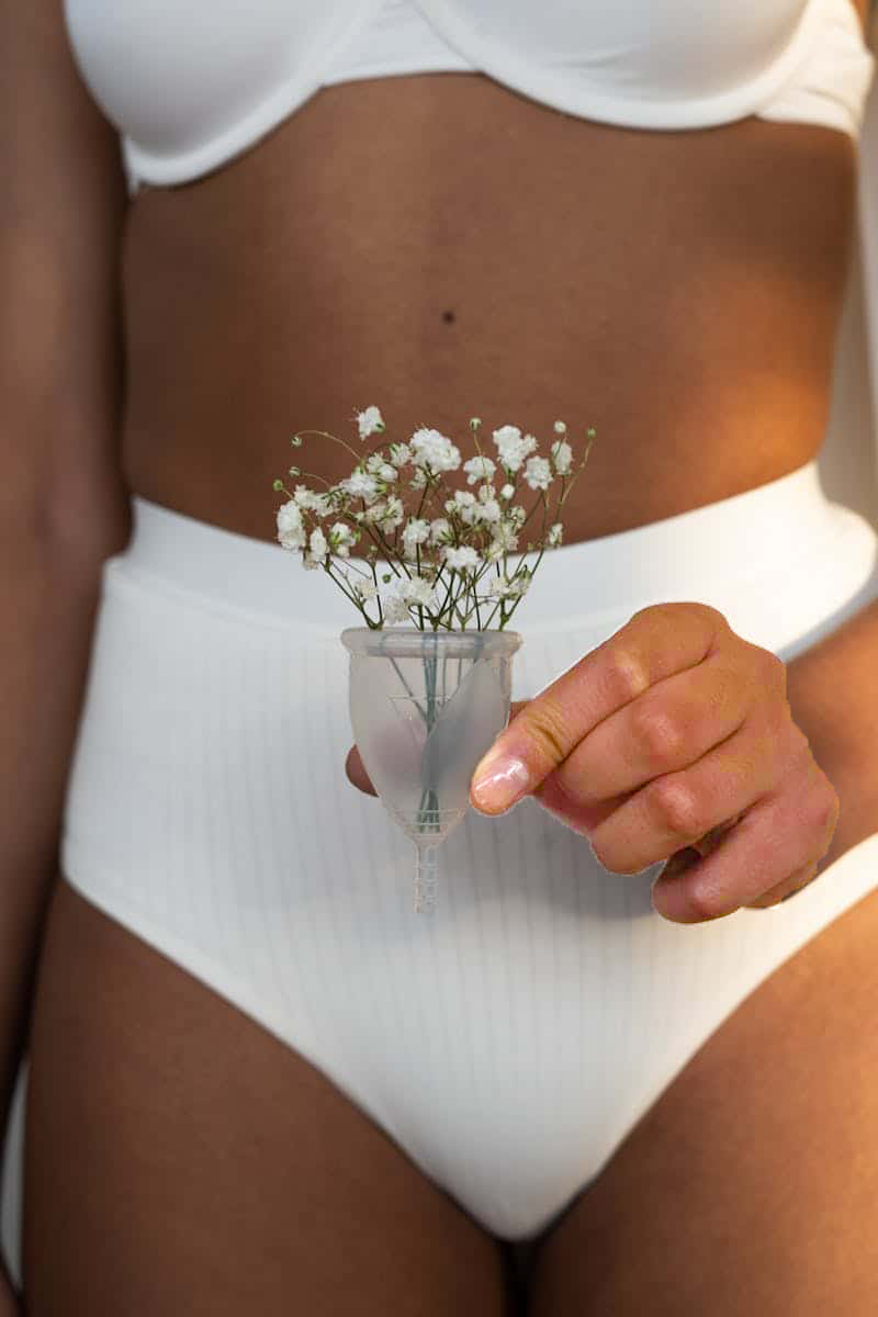 Woman in White Undergarments Holding Menstrual Cup with Flowers